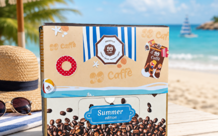 Confezione di cialde 99 Caffè Summer Edition su un tavolo in spiaggia, con ombrellone, mare e cappello di paglia